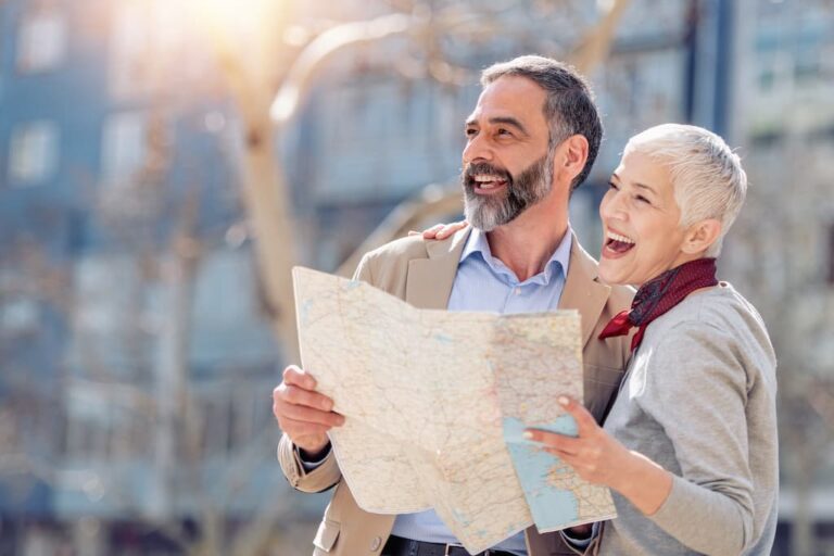 Un cuplu senior se uită bucuros la o hartă înainte de a călători.