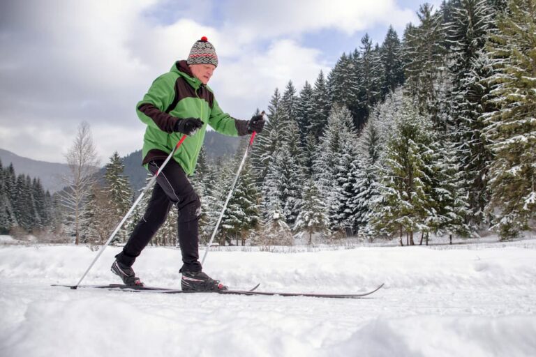 Un domn în vârstă face drumeții în sezonul rece pe munte.